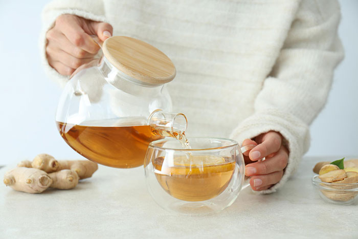 Sipanje zlatnog čaja iz staklenog čajnika na stolu.