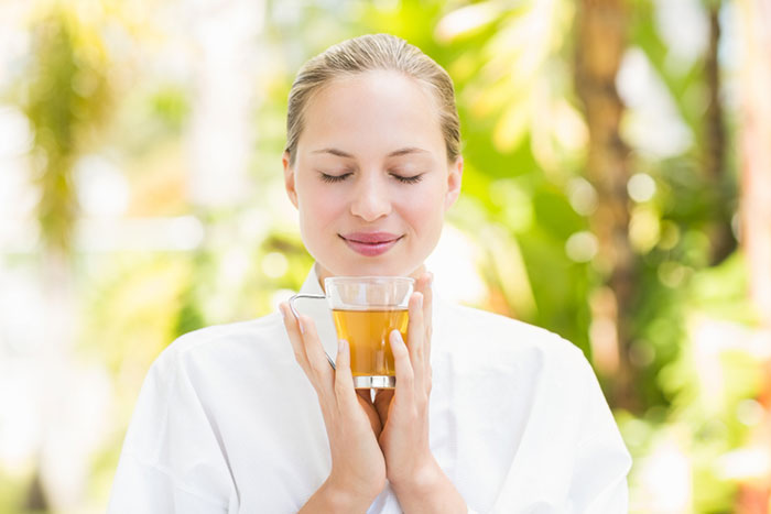 Žena uživa u mirisu čaja za mršavljenje u prirodnom okruženju.